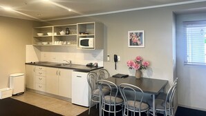 Une cuisine compacte avec des meubles blancs, un four à micro-ondes encastré et un coin repas équipé de quatre chaises.