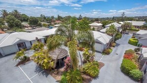 A residential area with houses, a central garden with palm trees, and a gazebo. - Annand Mews Serviced Apartments (Harristown)