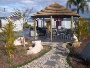 Un gazebo con tetto di paglia, circondato da posti a sedere all'aperto e palme.