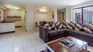 A modern living room with a sofa set, a coffee table, and a TV. - Annand Mews Serviced Apartments (Harristown)