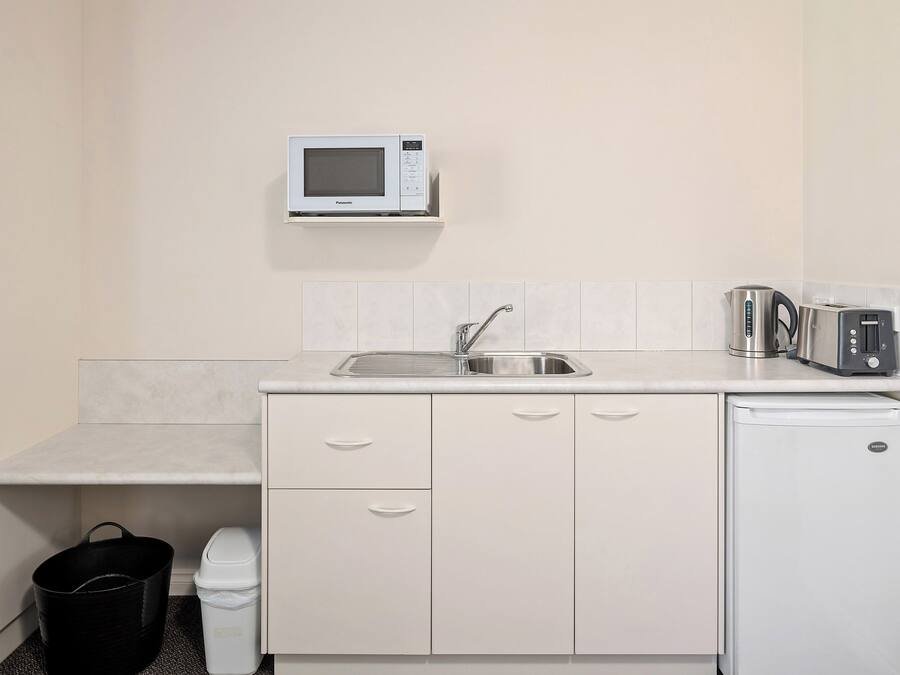 Une petite cuisine équipée d’un four à micro-ondes, d’un grille-pain, d’un évier et d’un petit réfrigérateur.
