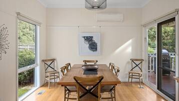 Un comedor con una mesa de madera, seis sillas, un bol negro y una obra de arte enmarcada en la pared.