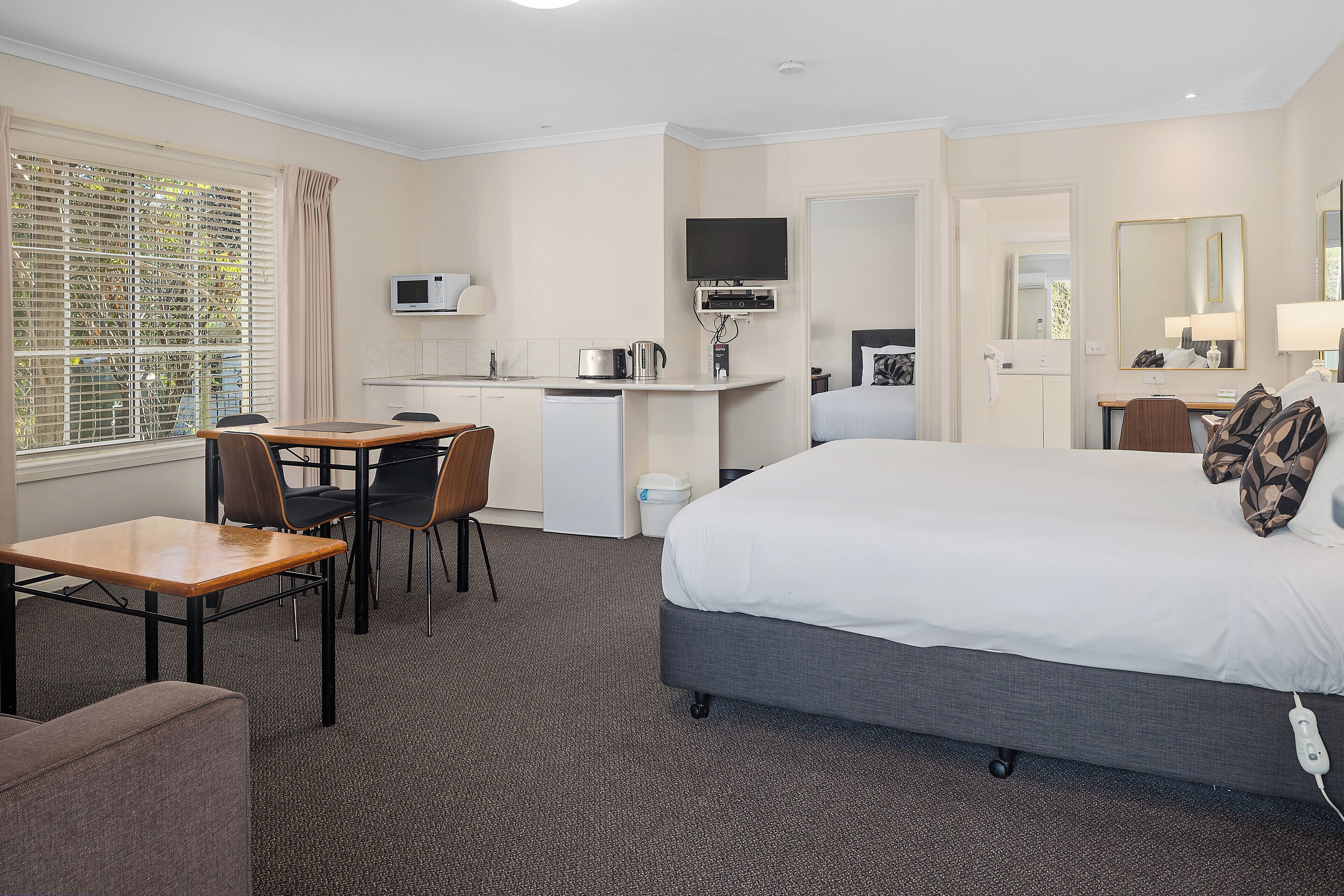 Una habitación de hotel con cama, escritorio, silla, televisor y microondas.