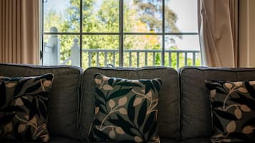 A sofa with patterned cushions and a view of a balcony with a railing.