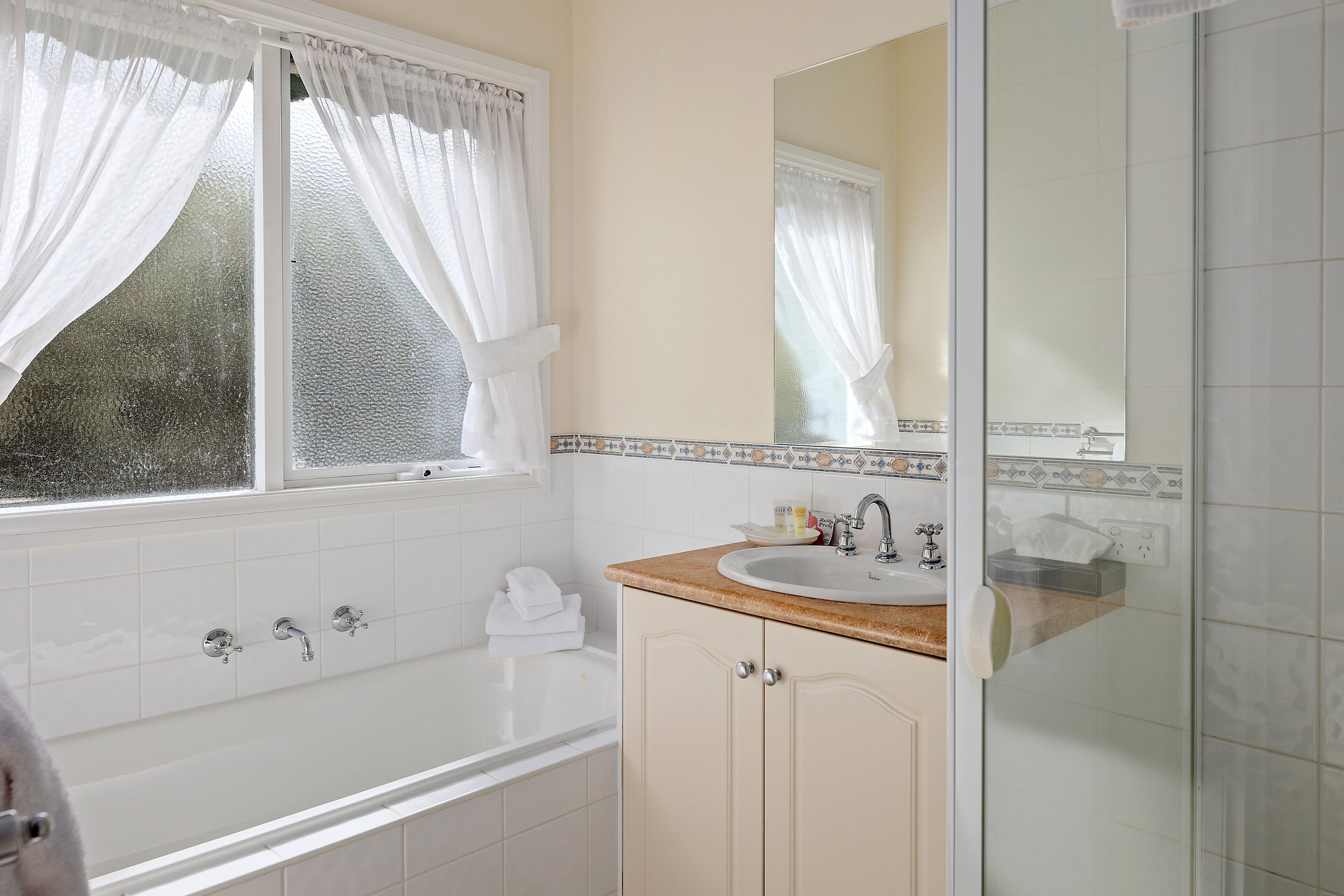 A bathroom with a bathtub, a sink, and a mirror.