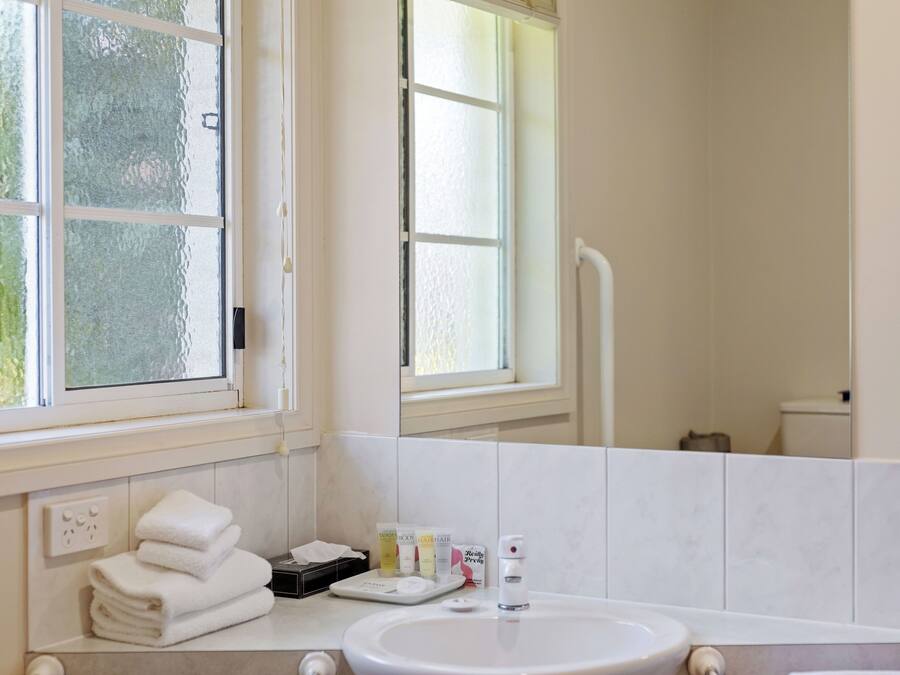 Ein Badezimmer mit Waschbecken, Pflegeprodukten und einem Fenster.
