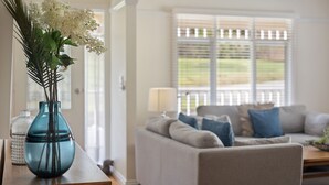 A living room with a sofa, cushions, a lamp, and a vase with flowers on a wooden table. - Yarra Gables (Healesville)