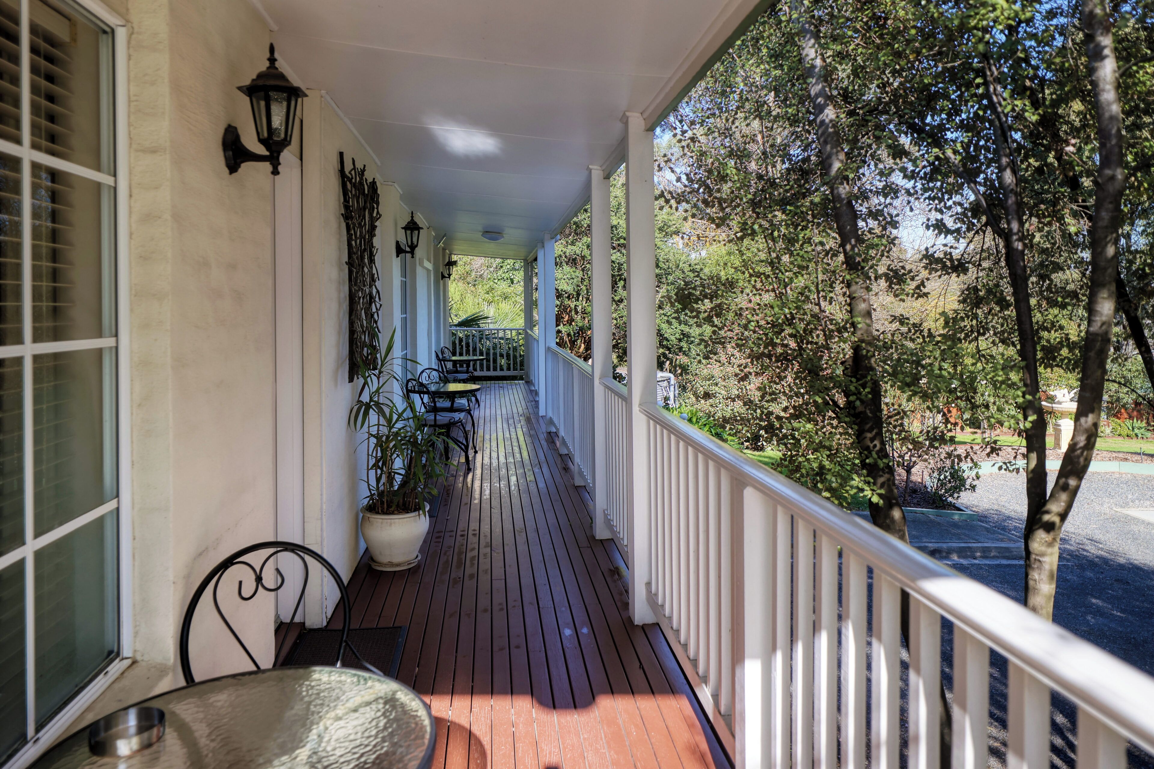 Eine hölzerne Veranda mit Geländer, Tisch und Stühlen.