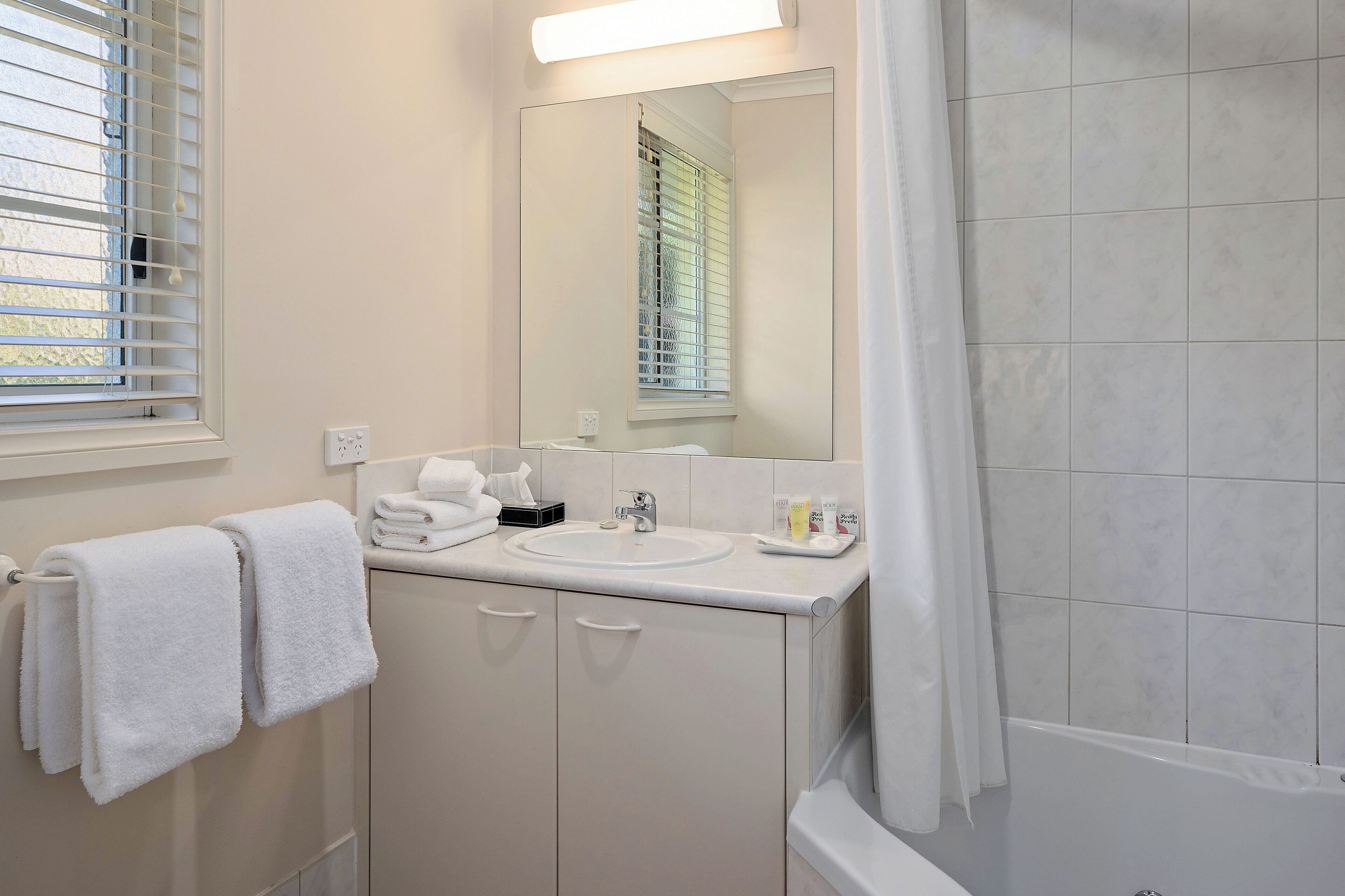 A bathroom with a sink, mirror, and shower.