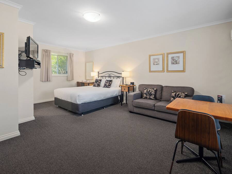 Ein Hotelzimmer mit Bett, Sofa, Schreibtisch und Stuhl.