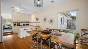 A modern kitchen with wooden cabinets, a central island, and bar stools. - Yarra Gables (Healesville)