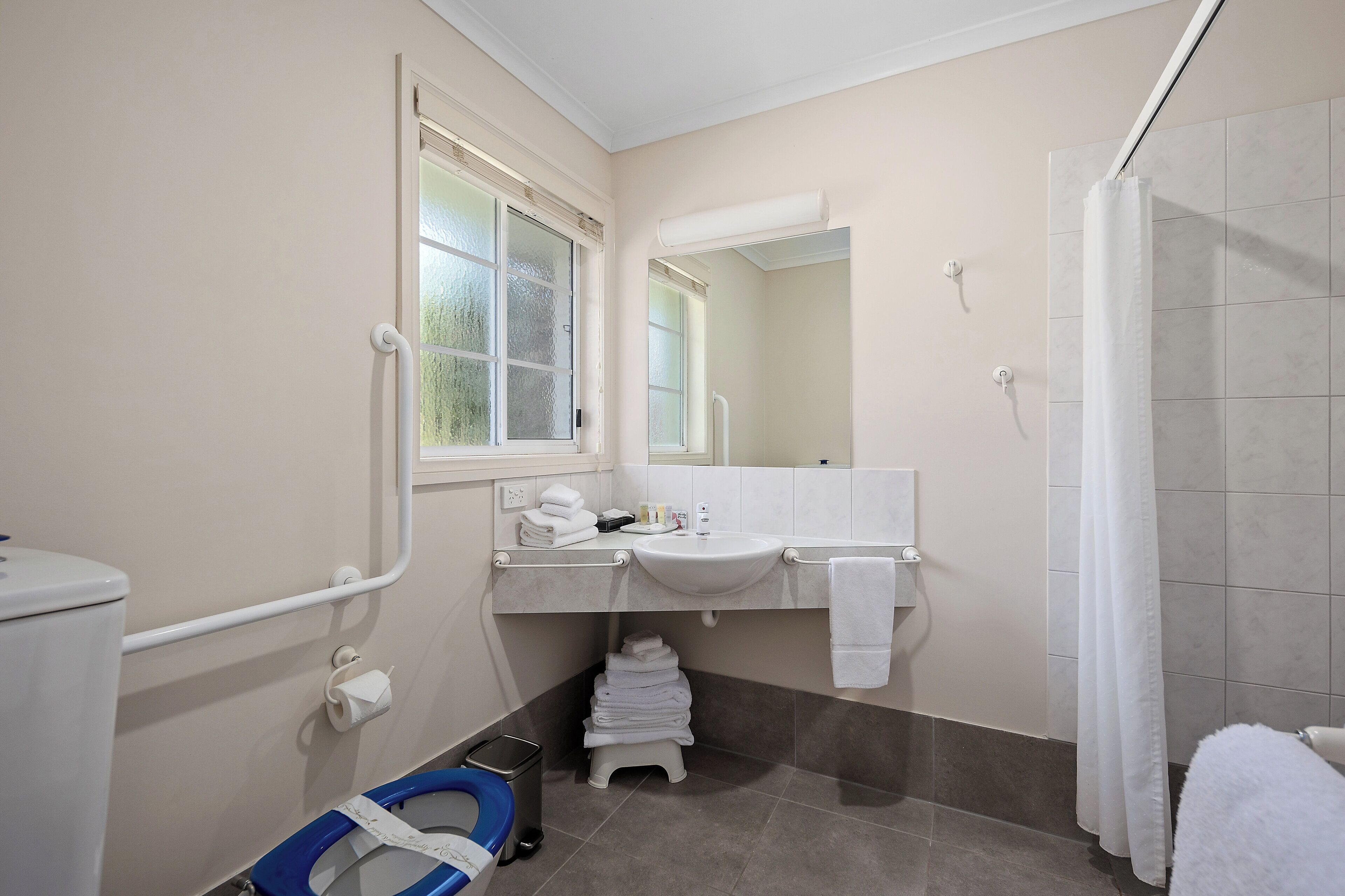 A bathroom with a toilet, sink, mirror, and shower curtain.