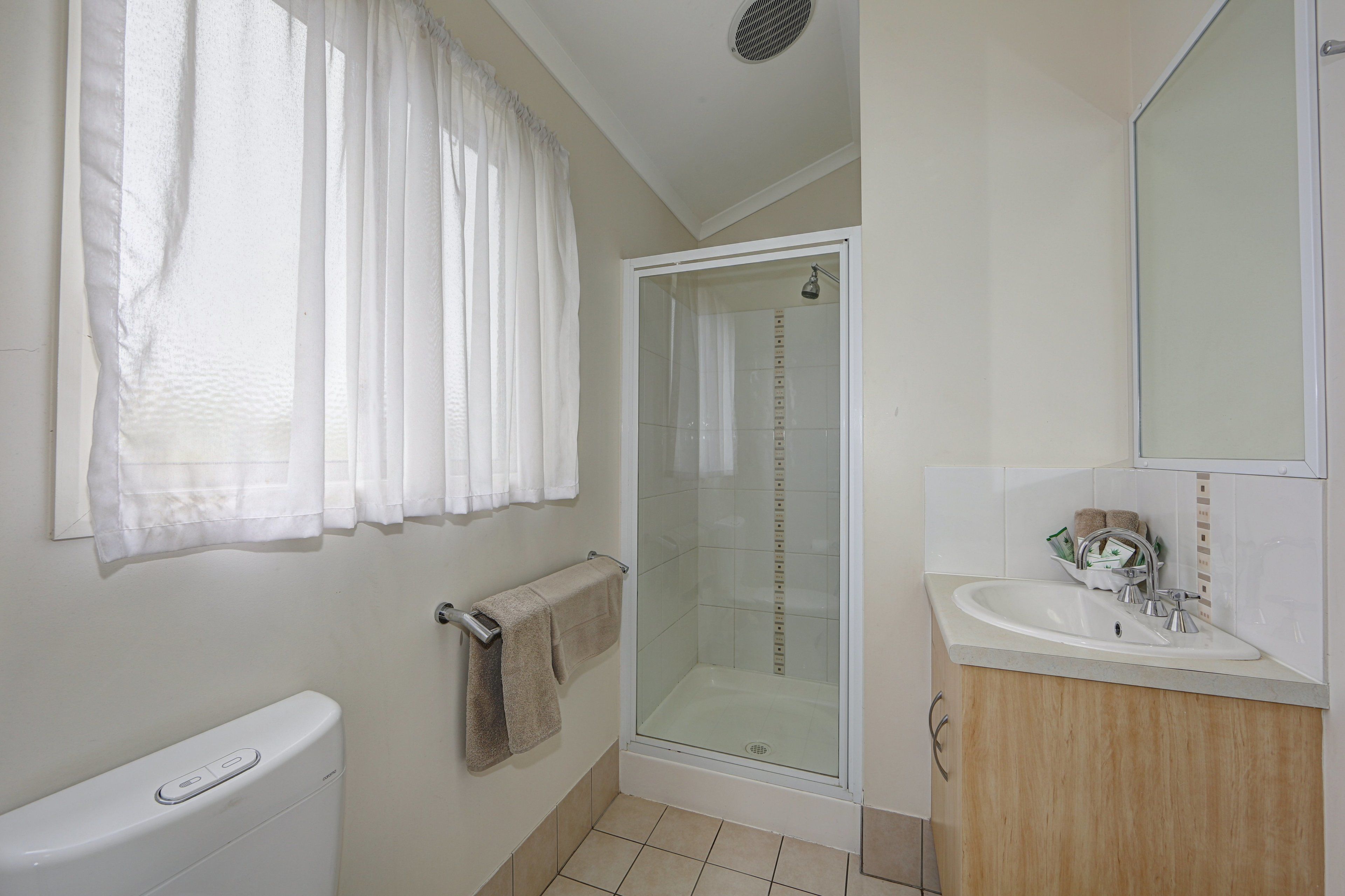 Un baño con ducha envuelta en vidrio, inodoro, lavabo y espejo.