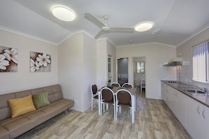 A modern kitchen with white cabinets, a built-in stove, and a window with blinds. - Dalby Tourist Park (Dalby)