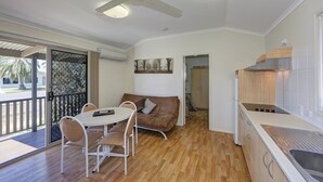 Uma cozinha compacta com área de jantar, ventilador de teto e vista através de uma porta de vidro.