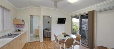 Un espacio habitable compacto con cocina, comedor y zona de estar con sofá y sillones.