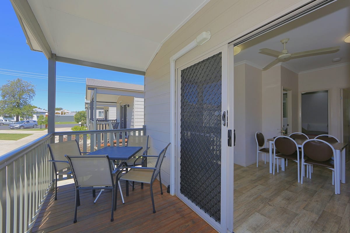A covered outdoor patio with a table and chairs, a sliding glass door leading to an interior dining area with a ceiling fan.