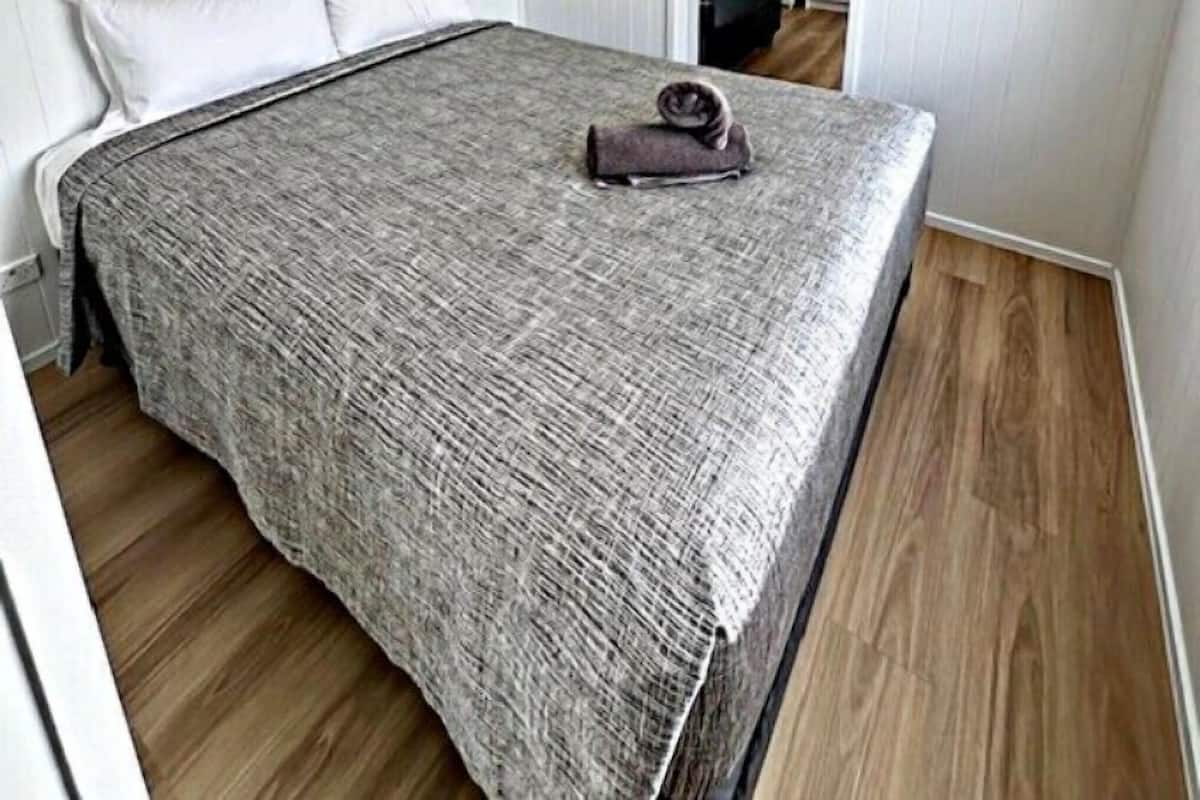 A bedroom with a bed, a ceiling fan, and a wooden floor.