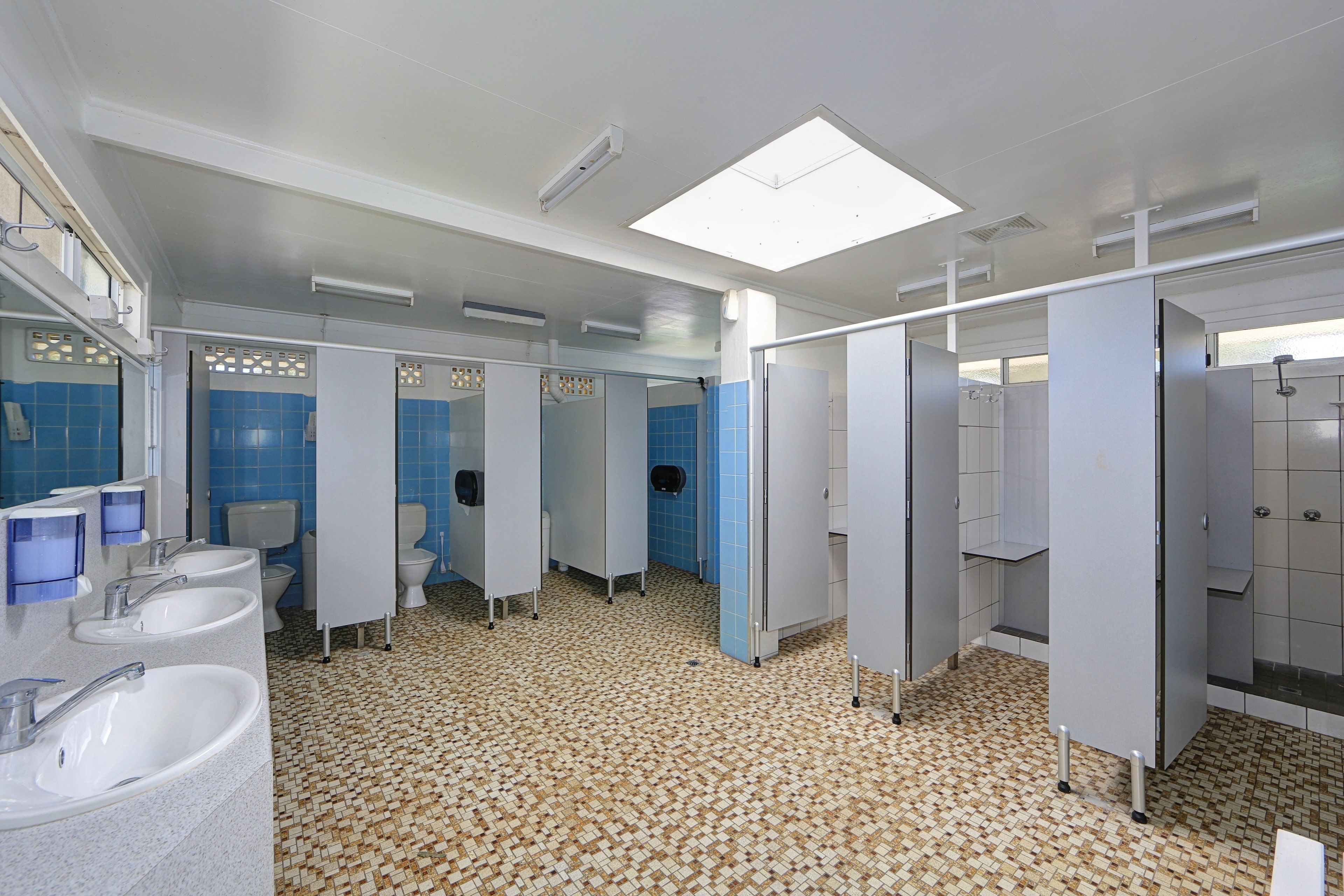A public restroom with multiple sinks, toilets, and privacy partitions.
