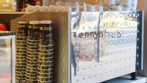 Uma máquina de café com várias xícaras e uma pilha de xícaras com a marca.