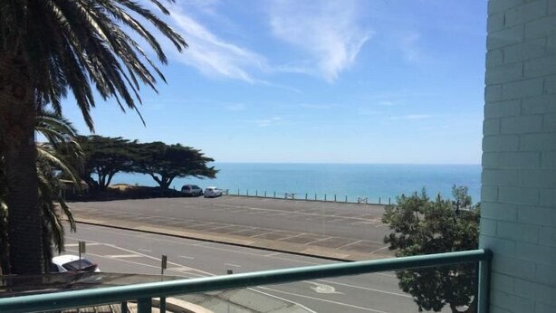Uma varanda com vista para um estacionamento e o oceano.