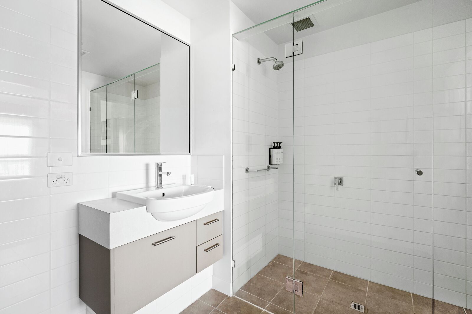 Un baño moderno con cabina de ducha de vidrio, un lavabo blanco y un espejo grande.