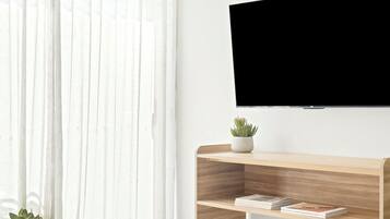 Una sala de estar moderna con un televisor de pared, una mesa consola de madera, una mesa redonda de centro y un sofá azul.