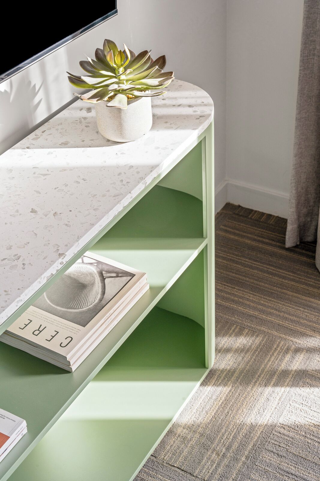 A modern room with a white marble shelf, a green shelf with a book, and a potted plant.
