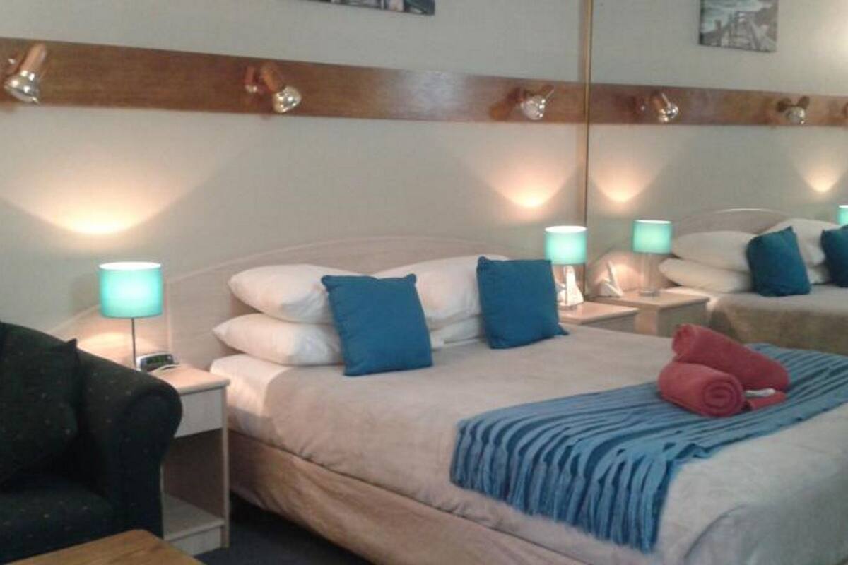 A hotel room with a bed, two bedside tables, a chair, and a mirror on the wall.