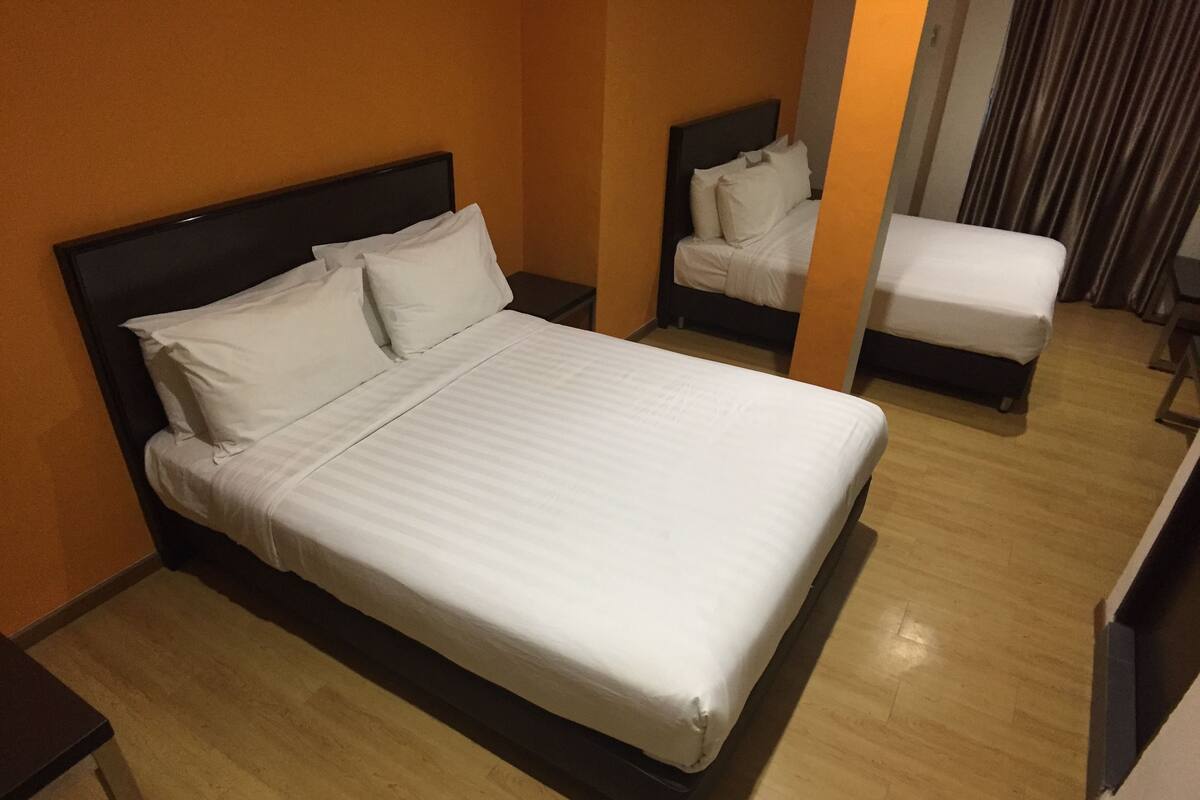 A hotel room with a large bed, a smaller bed, and a nightstand.