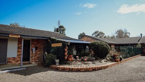 A reception area with a sign, a gravel driveway, and a brick border. - Denman Motor Inn (Denman)