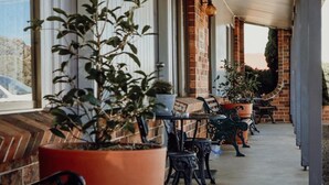 A covered outdoor area with brick walls, potted plants, and outdoor seating. - Denman Motor Inn (Denman)