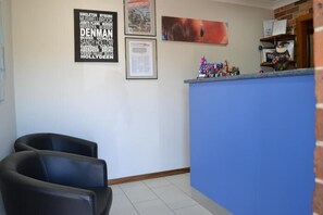 A reception area with a blue counter, black chairs, and various framed items on the wall.