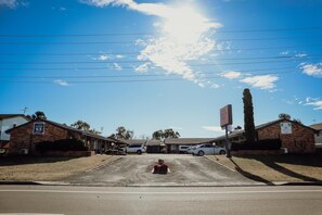 A parking lot with several cars, a building with a sign, and a clear blue sky.