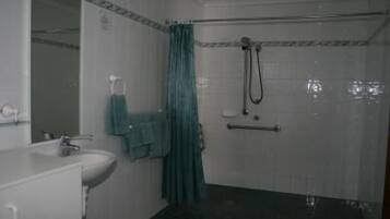 A bathroom with a sink, mirror, and shower.