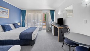 A hotel room with a bed, a desk, a chair, a television, and a view of the outdoors. - The River Boat Hotel - Echuca (Echuca)