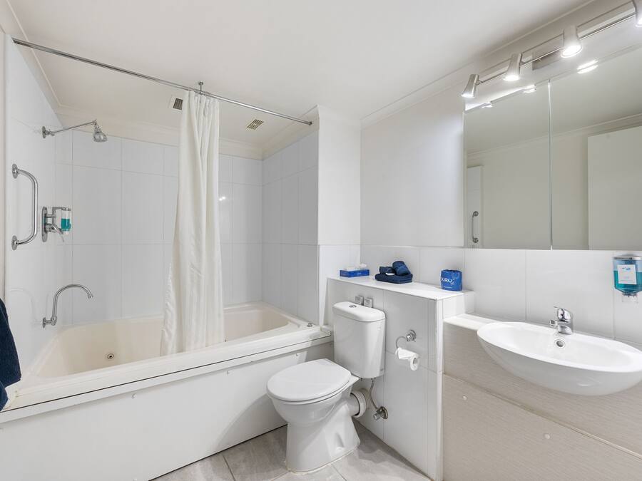 Une salle de bain moderne avec une baignoire, des toilettes, un lavabo et un grand miroir.