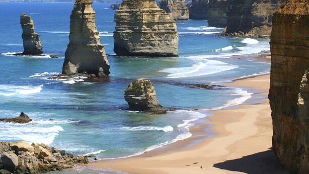 Un paysage côtier caractérisé par d’imposantes formations rocheuses et une plage de sable.