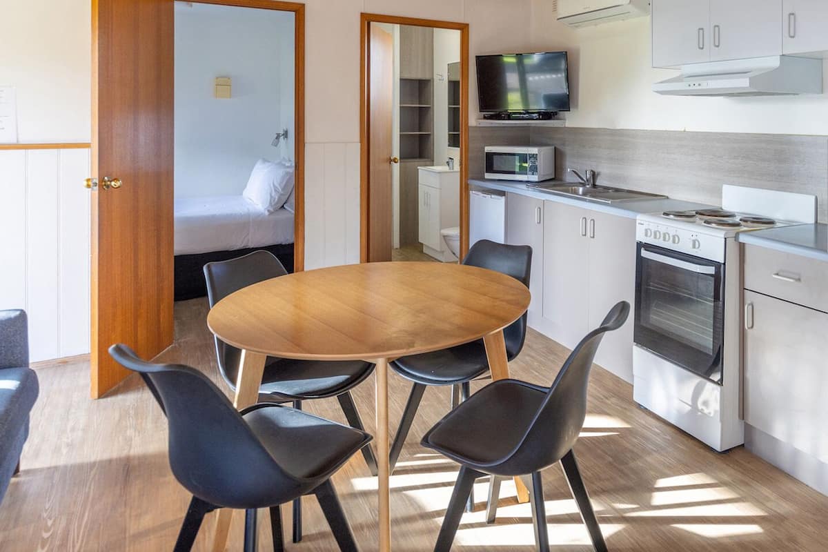 Cocina compacta con comedor, techo de madera y electrodomésticos integrados.
