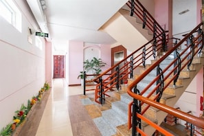 A hotel lobby with a staircase, a reception desk, and a plant. - Golden Gate 1 Hotel Da Nang (Da Nang)