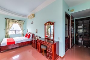 A bedroom with a bed, a wooden dresser, a mirror, and a door. - Golden Gate 1 Hotel Da Nang (Da Nang)