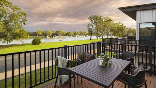 A deck with outdoor seating, a view of a lake, and a building with large windows. - Berri Hotel (Berri)