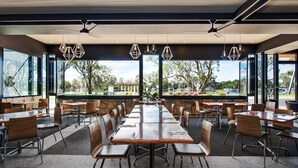 A modern dining area with large windows, multiple tables, and chairs. - Berri Hotel (Berri)