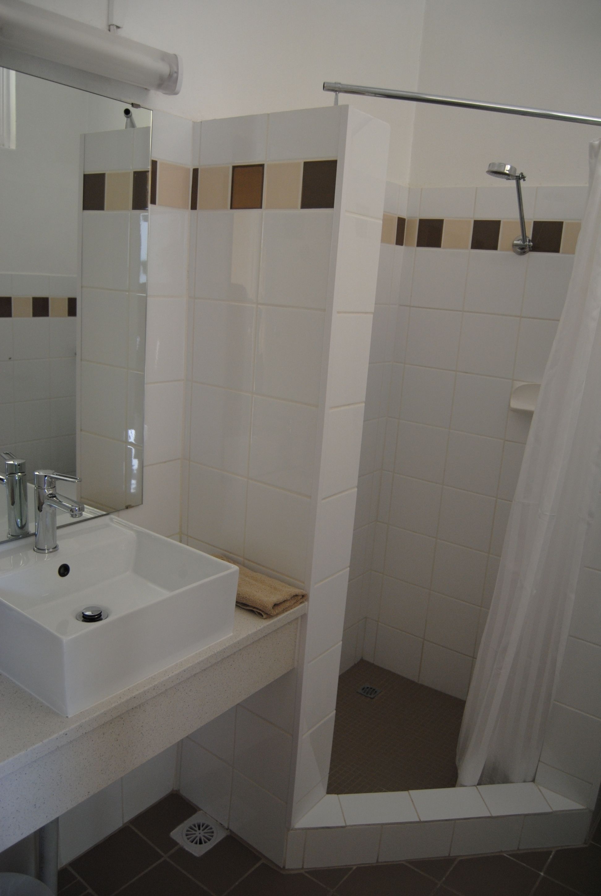 A bathroom with a white sink, mirror, and shower area.