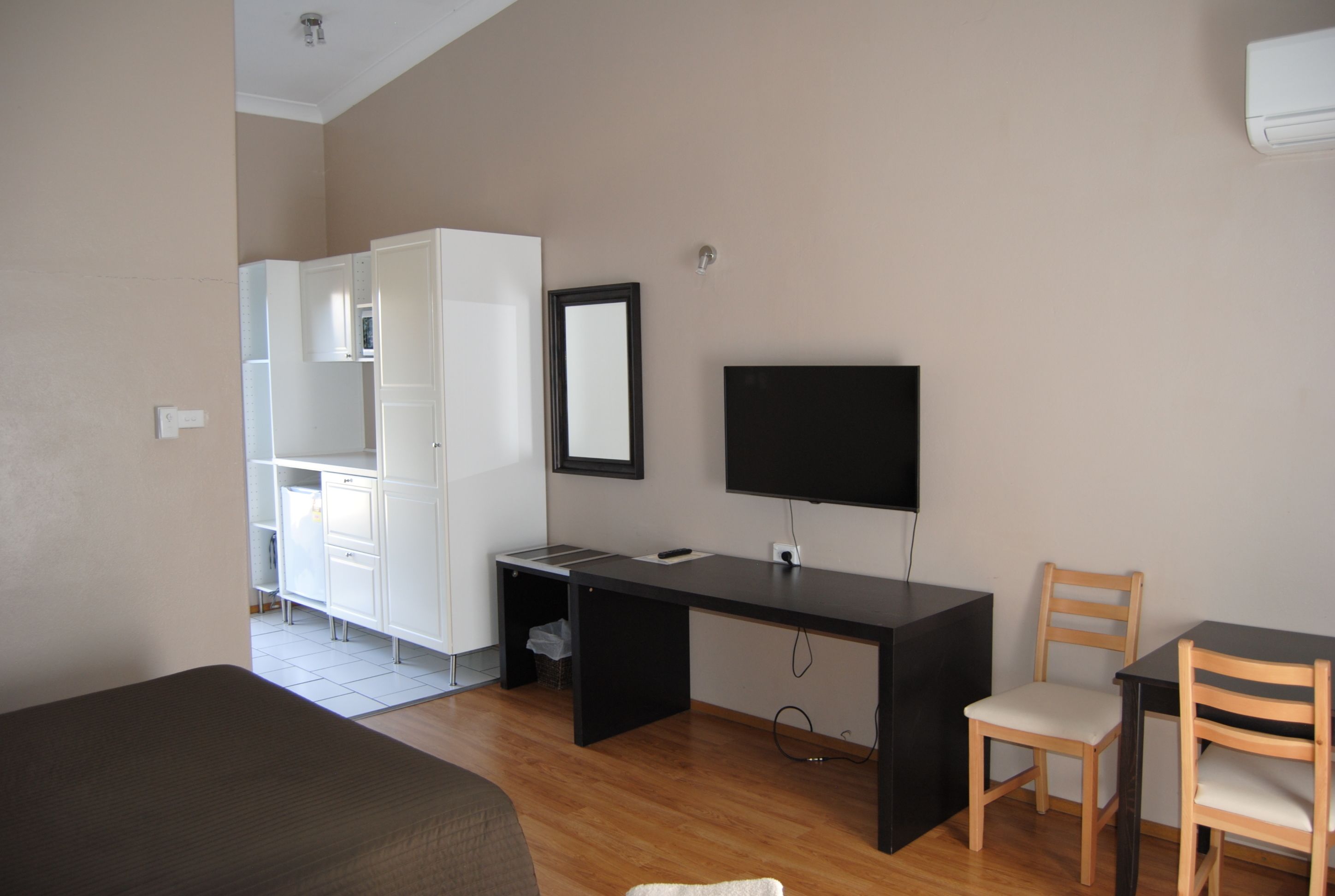 A room with a bed, a desk with a chair, a TV, and a wardrobe.