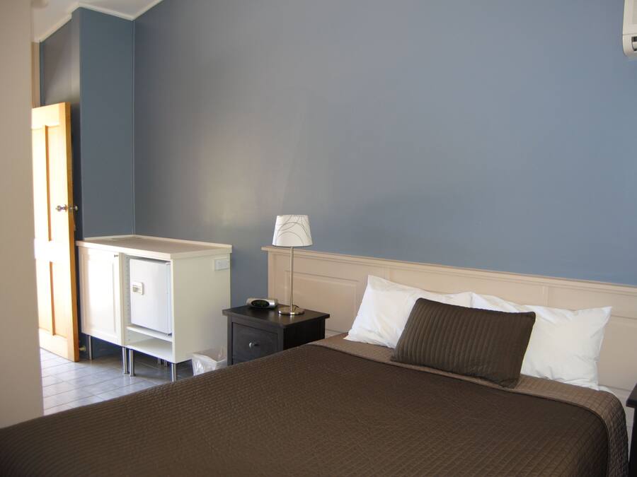 A bedroom with a bed, bedside table, lamp, and a wardrobe.