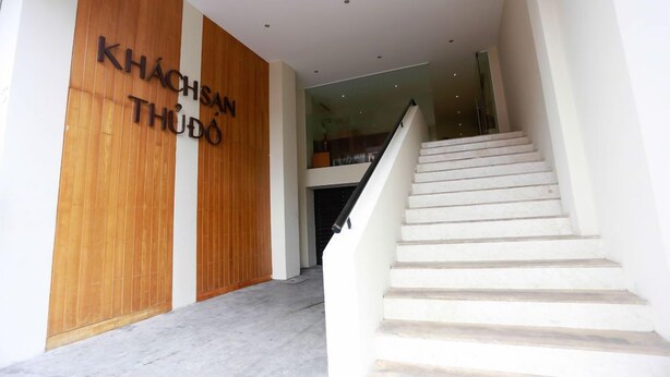 Una entrada moderna a un edificio con fachada de madera y una escalera que conduce a un nivel superior.