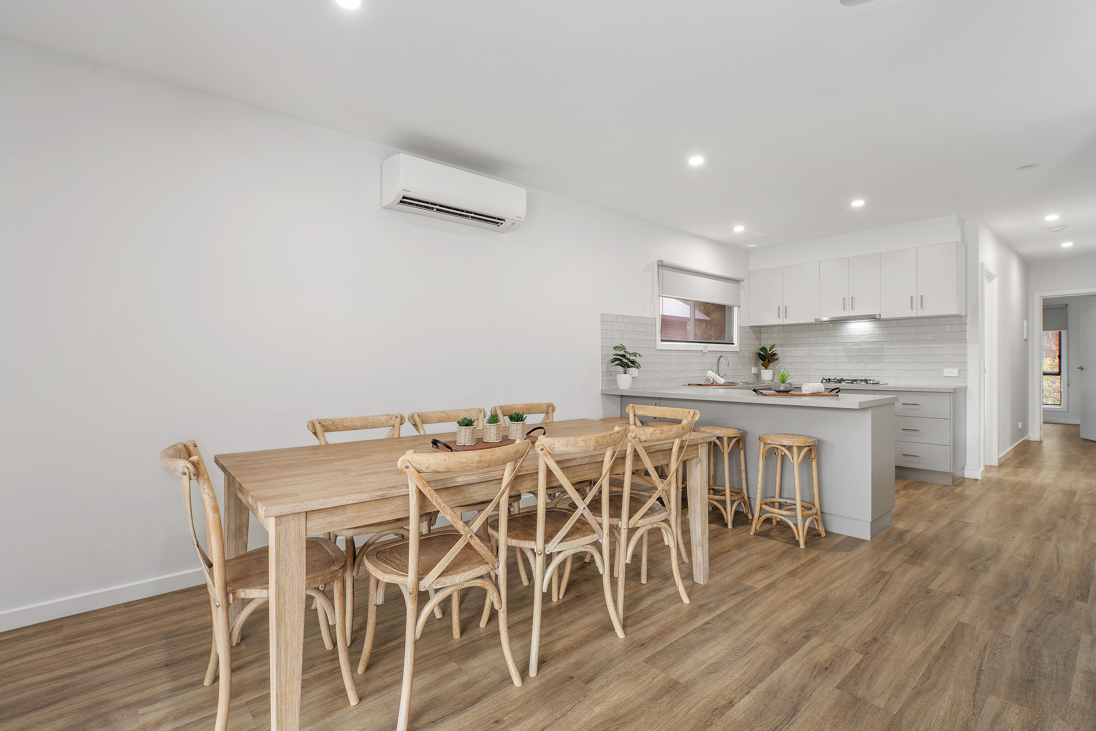 Una cocina moderna con armarios blancos, una mesa de comedor de madera y una isla central con taburetes.
