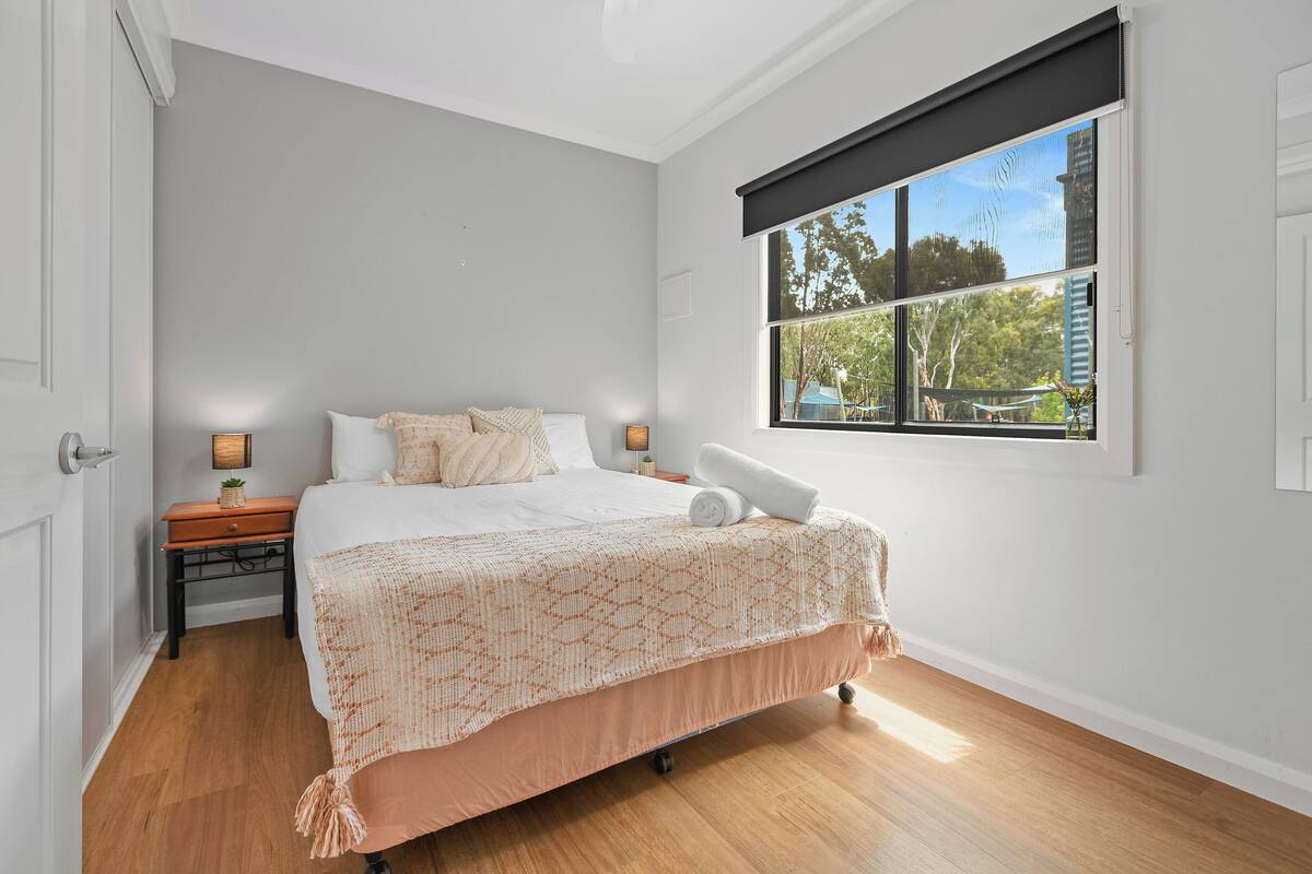 A bedroom with a bed, a nightstand, a window, and a door.