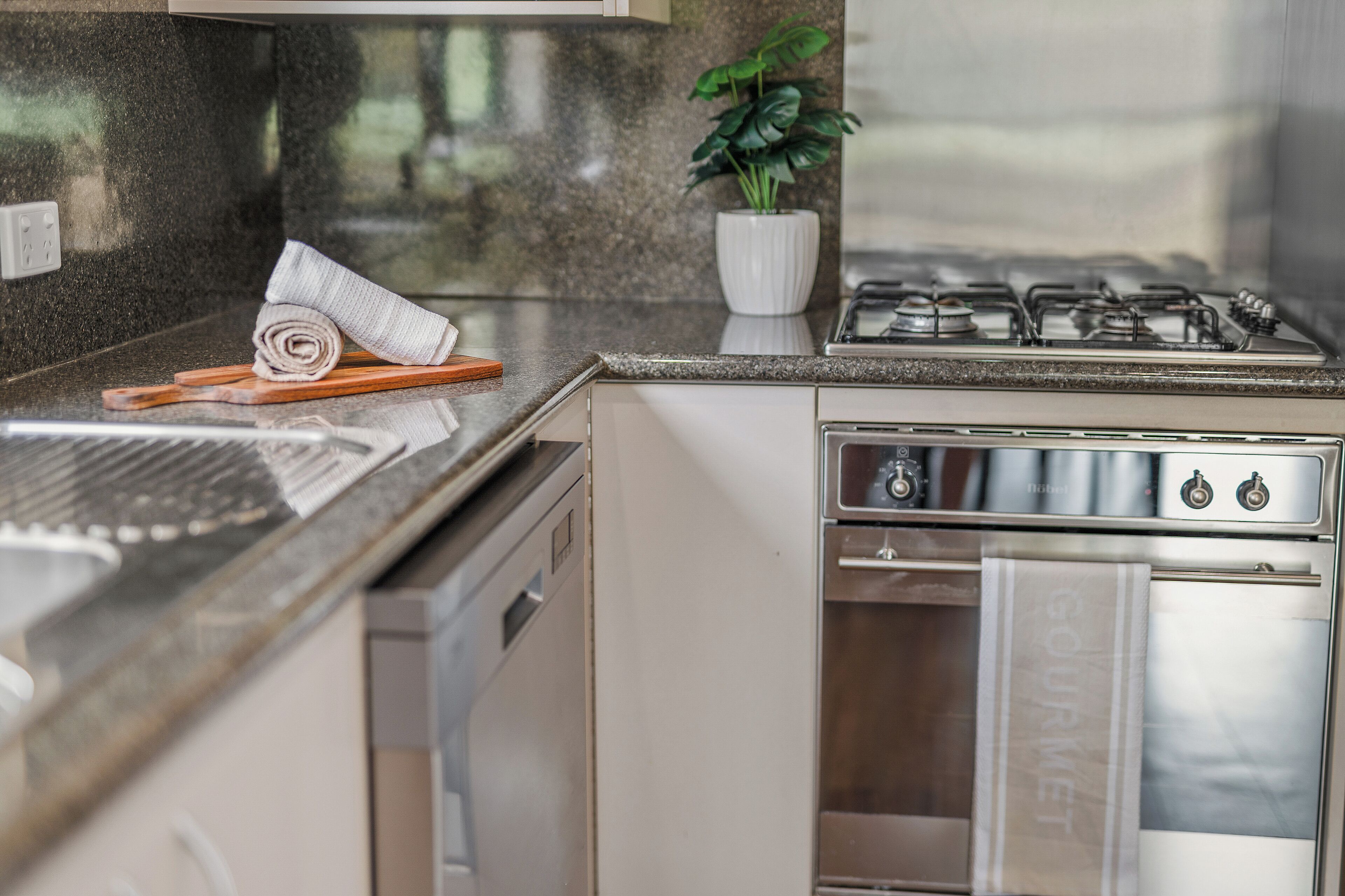 Una cocina moderna con estufa de acero inoxidable, horno empotrado y lavavajillas.